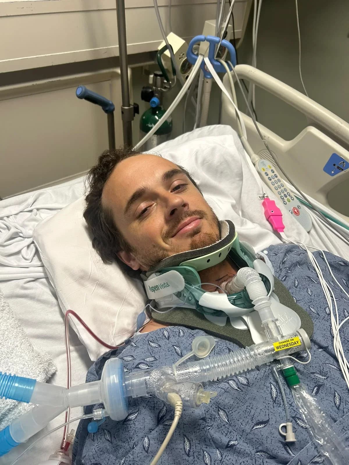 Guillermo smiling from his hospital bed, still on breathing support